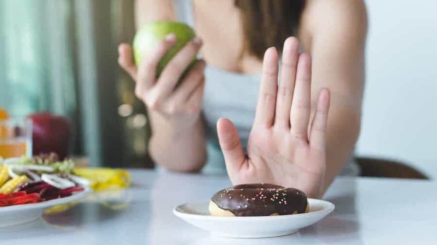 woman on a diet pushing away a donut as she eats an apple