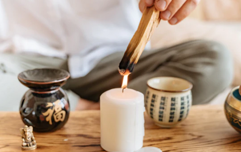 A man lighting a piece of wood with a lit candle. Source: NI Candle Supplies.