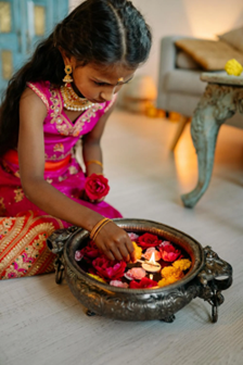 An Indian girl lighting a floating candle in a bowl of water with flower petals. Source: <span data-mce-fragment="1"><a href="https://www.pexels.com/photo/girl-lighting-a-tealight-candle-8819116/" data-mce-fragment="1" data-mce-href="https://www.pexels.com/photo/girl-lighting-a-tealight-candle-8819116/">Pexels</a></span>.