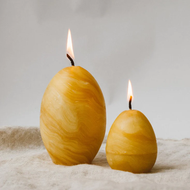 A pair of golden, marbled egg-shaped candles in different sizes from <span data-mce-fragment="1"><a href="https://consciouscraft.uk/products/happy-easter-candle-set-of-4" data-mce-fragment="1" data-mce-href="https://consciouscraft.uk/products/happy-easter-candle-set-of-4">Conscious Craft</a></span>.