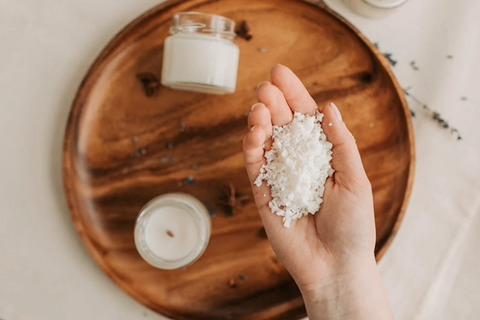 An overhead shot of a person holding candle wax with candles in the background. Sourced from <span data-mce-fragment="1"><a href="https://www.pexels.com/photo/person-holding-a-handful-of-candle-wax-6755754/" data-mce-href="https://www.pexels.com/photo/person-holding-a-handful-of-candle-wax-6755754/" data-mce-fragment="1">Pexels</a></span>