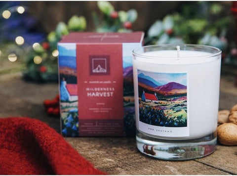 A "https://www.cairncandles.co.uk/shop/wilderness-harvest-art-candle/" candle featuring artwork of the Scottish highlands on the label and packaging.