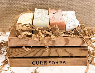 A wooden crate holding handmade soaps with ‘CURE SOAPS’ branded on the side. Sourced from <span data-mce-fragment="1"><a href="https://www.pinterest.co.uk/pin/782219029055984331/" data-mce-fragment="1" data-mce-href="https://www.pinterest.co.uk/pin/782219029055984331/">Pinterest</a></span>