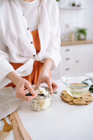 A person next to a bowl of melted candle wax and scooping out more wax. Sourced from <span data-mce-fragment="1"><a href="https://www.pexels.com/photo/a-person-scooping-candle-wax-from-a-glass-container-7234538/" data-mce-fragment="1" data-mce-href="https://www.pexels.com/photo/a-person-scooping-candle-wax-from-a-glass-container-7234538/">Pexels</a></span>.