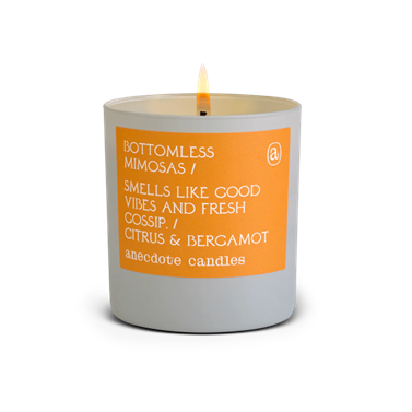 The ‘Bottomless Mimosas’ scented candle by <span data-mce-fragment="1"><a href="https://anecdotecandles.com/products/bottomless-mimosas" data-mce-fragment="1" data-mce-href="https://anecdotecandles.com/products/bottomless-mimosas">anecdote</a></span>, in a grey and orange vessel.
