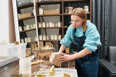 A woman in a candle shop making candles and packaging them. Sourced from Unsplash.