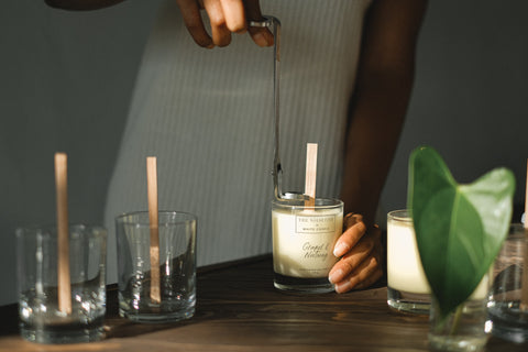 A zoomed-in shot of a person making candles with wooden wicks
