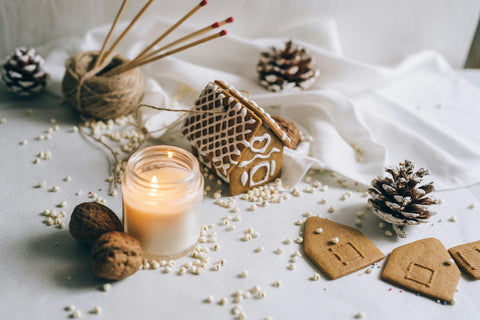 A handmade candle among a festive display of pine cones and gingerbread cookies. Sourced from Pexels.