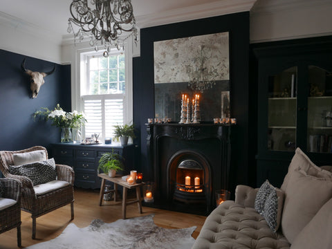 Moody decor-themed living room with pillar candles within and atop the fireplace.