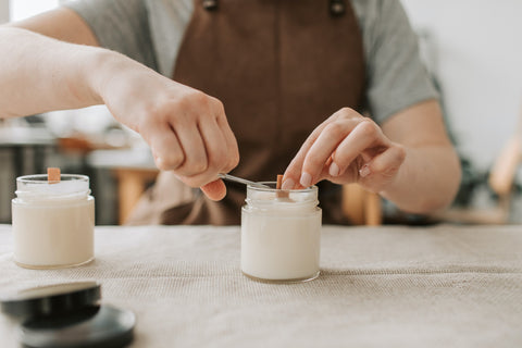 A zoomed-in photograph of a person trimming the wick of a handmade candle