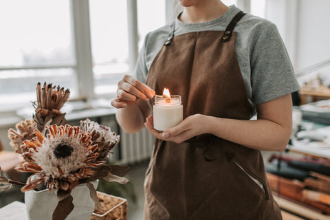 An artisan lighting a homemade candle. Sourced from Pexels.