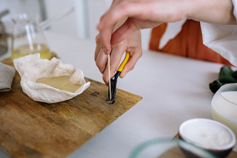 A person trimming a cotton candle wick with pliers. Sourced from Pexels.