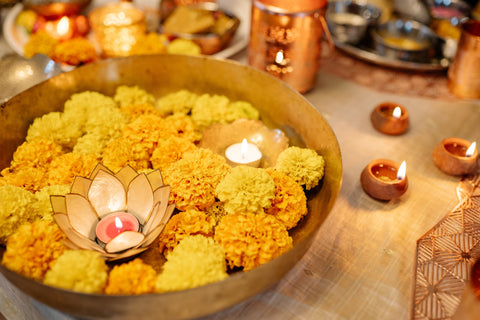 A bright yellow table set-up featuring flowers and Diwali tealight candles. Sourced from Pexels.