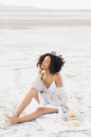 Model sitting on a towel over the sand.