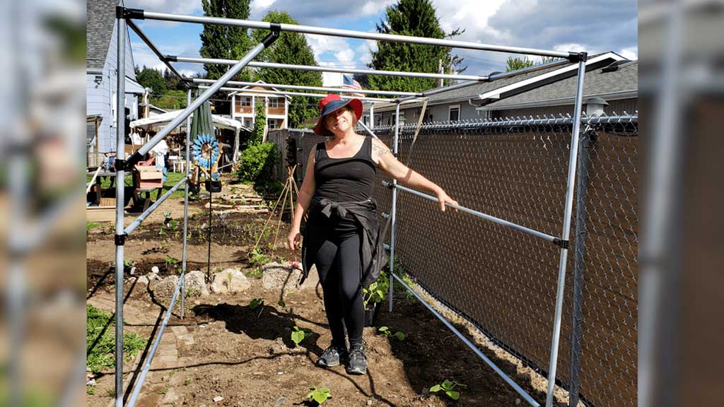 Woman standing proud next to her custom garden trellis