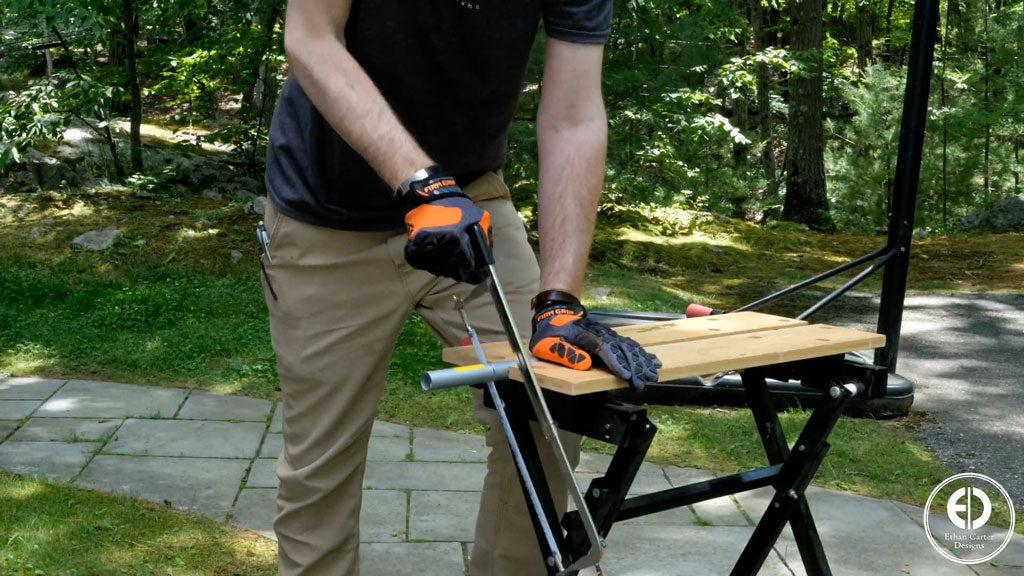 Man using hacksaw to cut electrical tubing in driveway