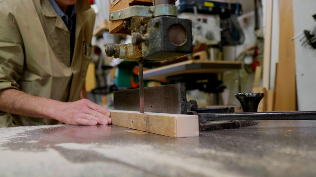 Woodworker using bandsaw to cut through wood inside of workshop