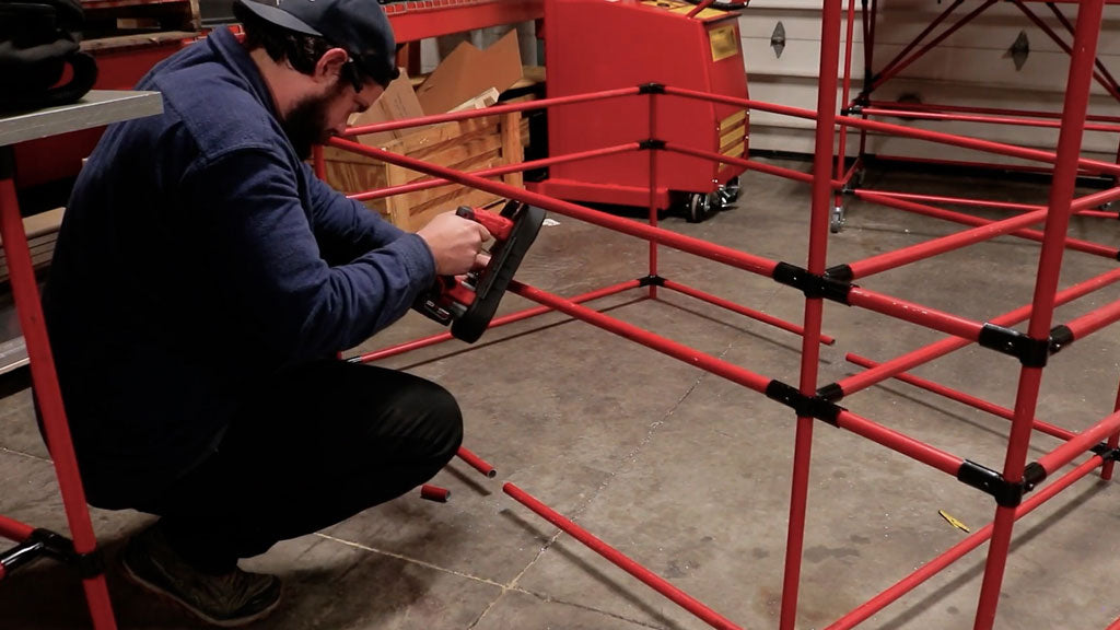 Man cutting emt conduit build into two halves with portable saw