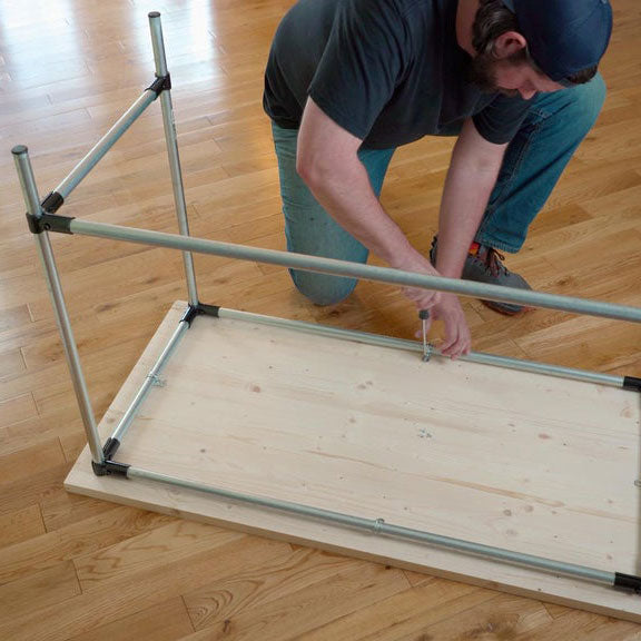 Man Securing Tabletop To DIY Desk Frame