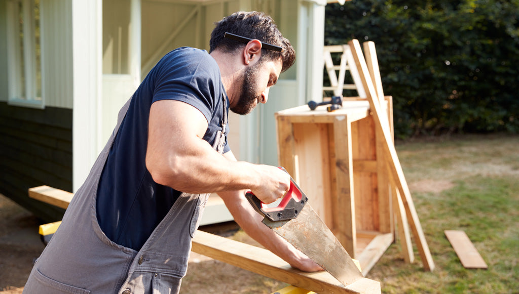 Male cutting wooden planks for raised garden bed