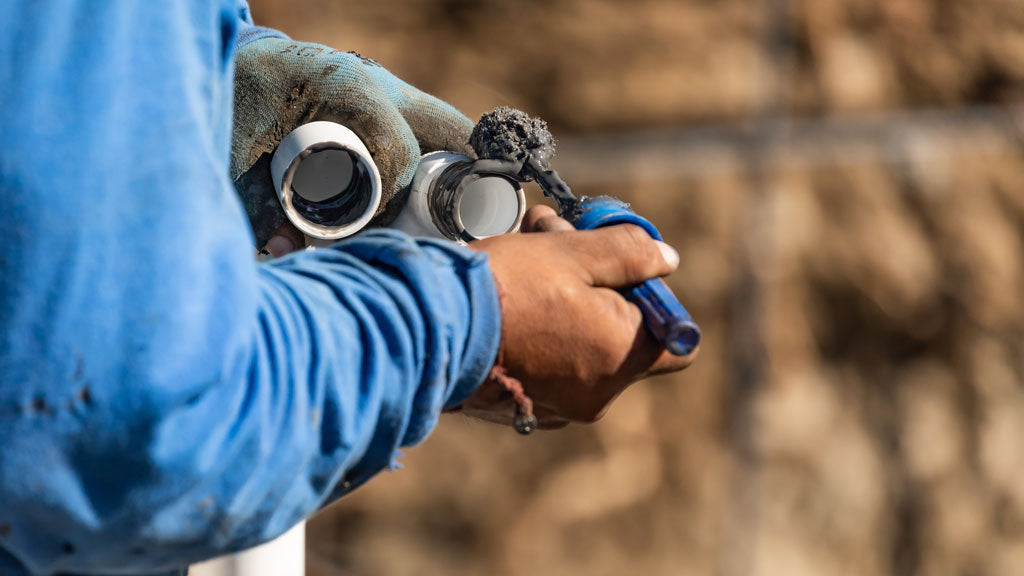 Man putting PVC glue onto pipes in the garden