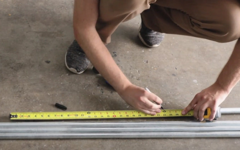 a man measuring and marking a piece of conduit