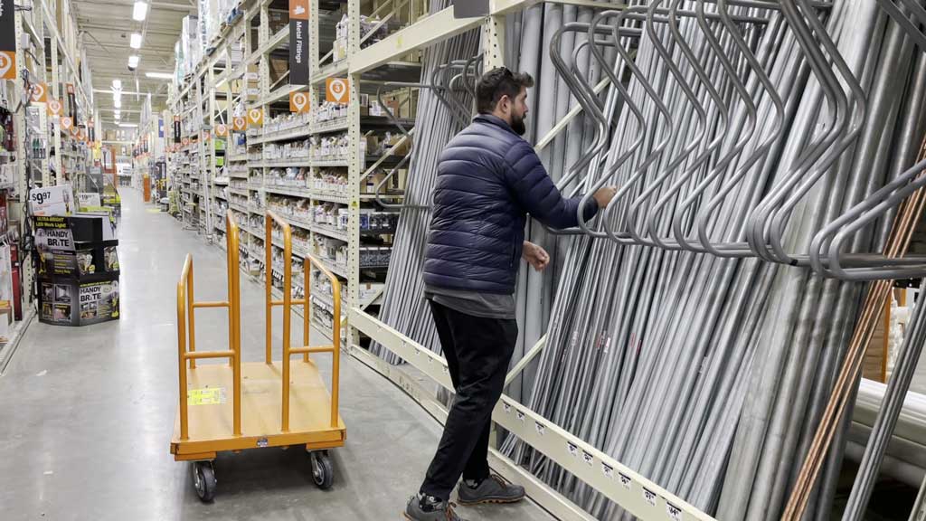 Man Grabbing Electrical Conduit Off The Shelf At Home Improvement Store