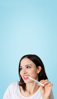 Woman with teeth whitening pen for brighter teeth.