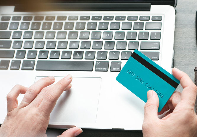 hands of a person shopping online for handmade soap using a credit card and laptop computer