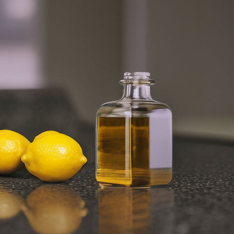 lemon essential oil in bottle next to whole lemons