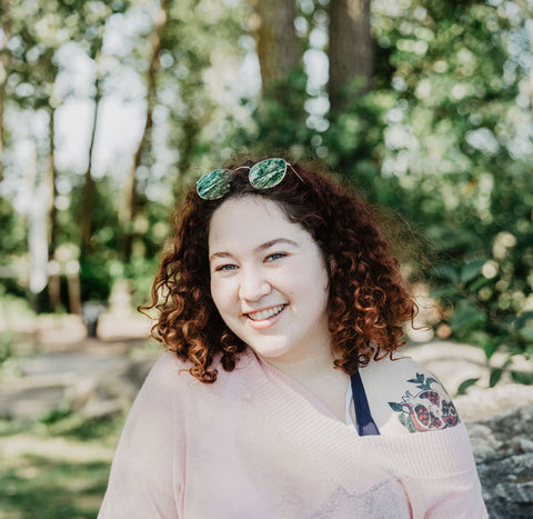 young woman with curly hair smiling while standing outdoors