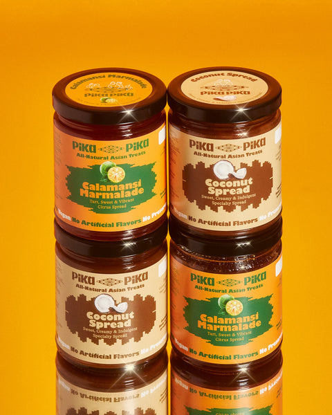 Two vertical stacks of Pika Pika products.  On top of the left stack is Pika Pika Calamansi Marmalade.  On top of the right stack is Pika Pika Coconut Spread.