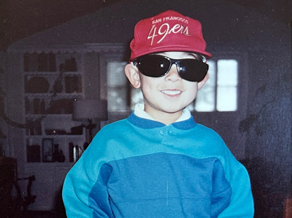 A headshot of Evan Lessler, the CEO of Adapt Clothing, as a child, wearing a San Francisco 49ers hat.