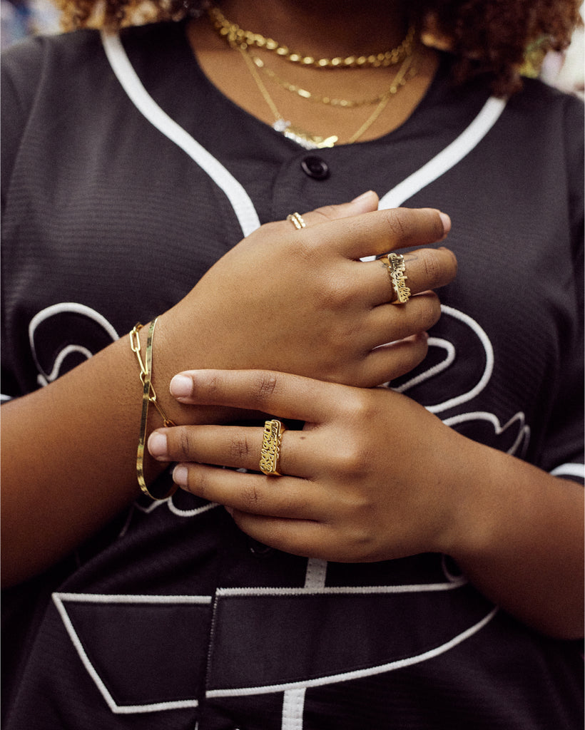  A closeup of a woman's hands and wrists in front of her chest, showcasing her Nunchi rings, bracelets, and necklaces.