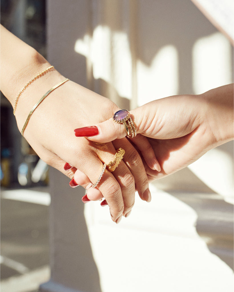 A close-up of two hands holding each other while wearing Nunchi jewelry.