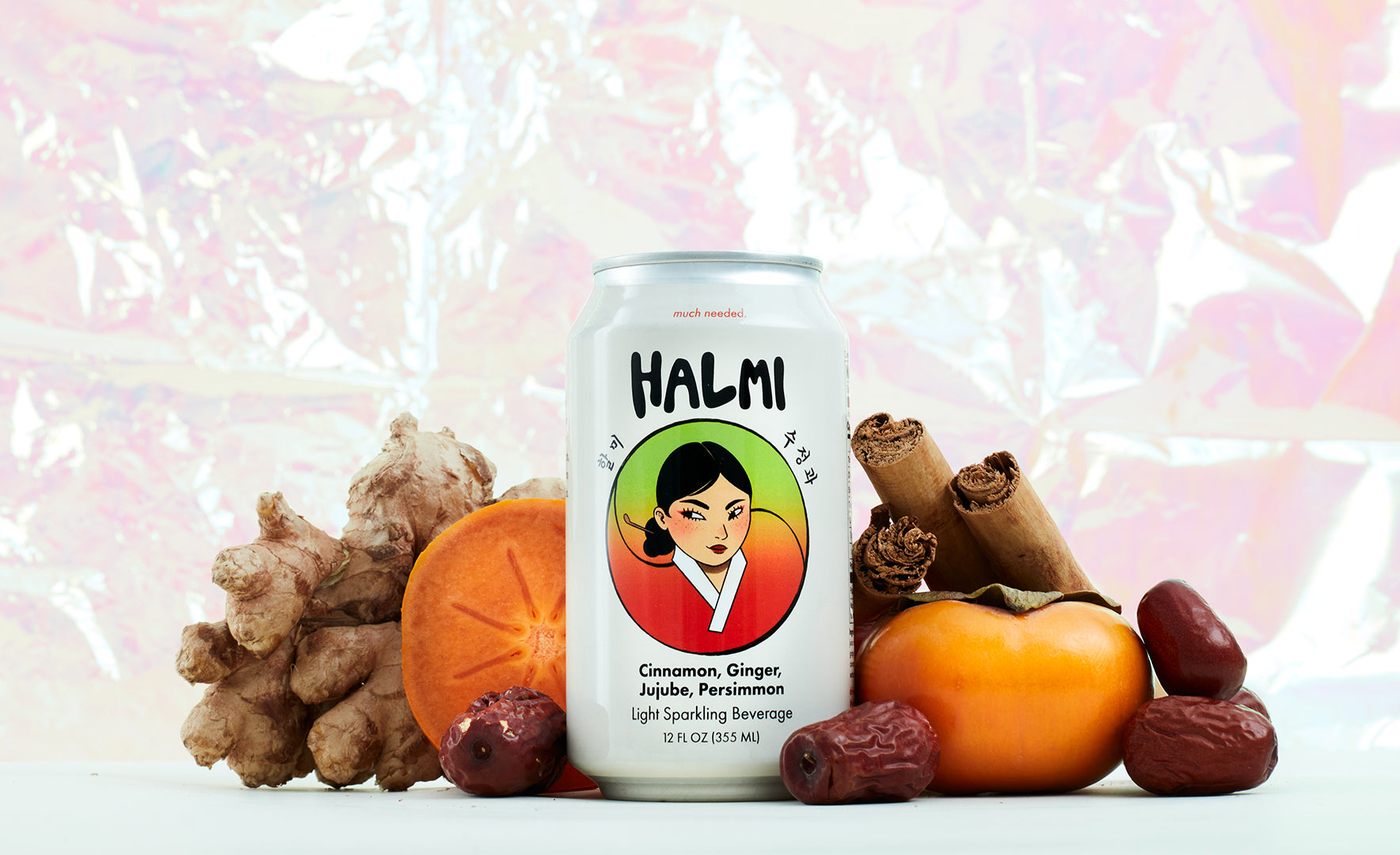 Halmi sparkling beverage on a table with pieces of ginger, persimmon, jujubes, and cinnamon sticks.