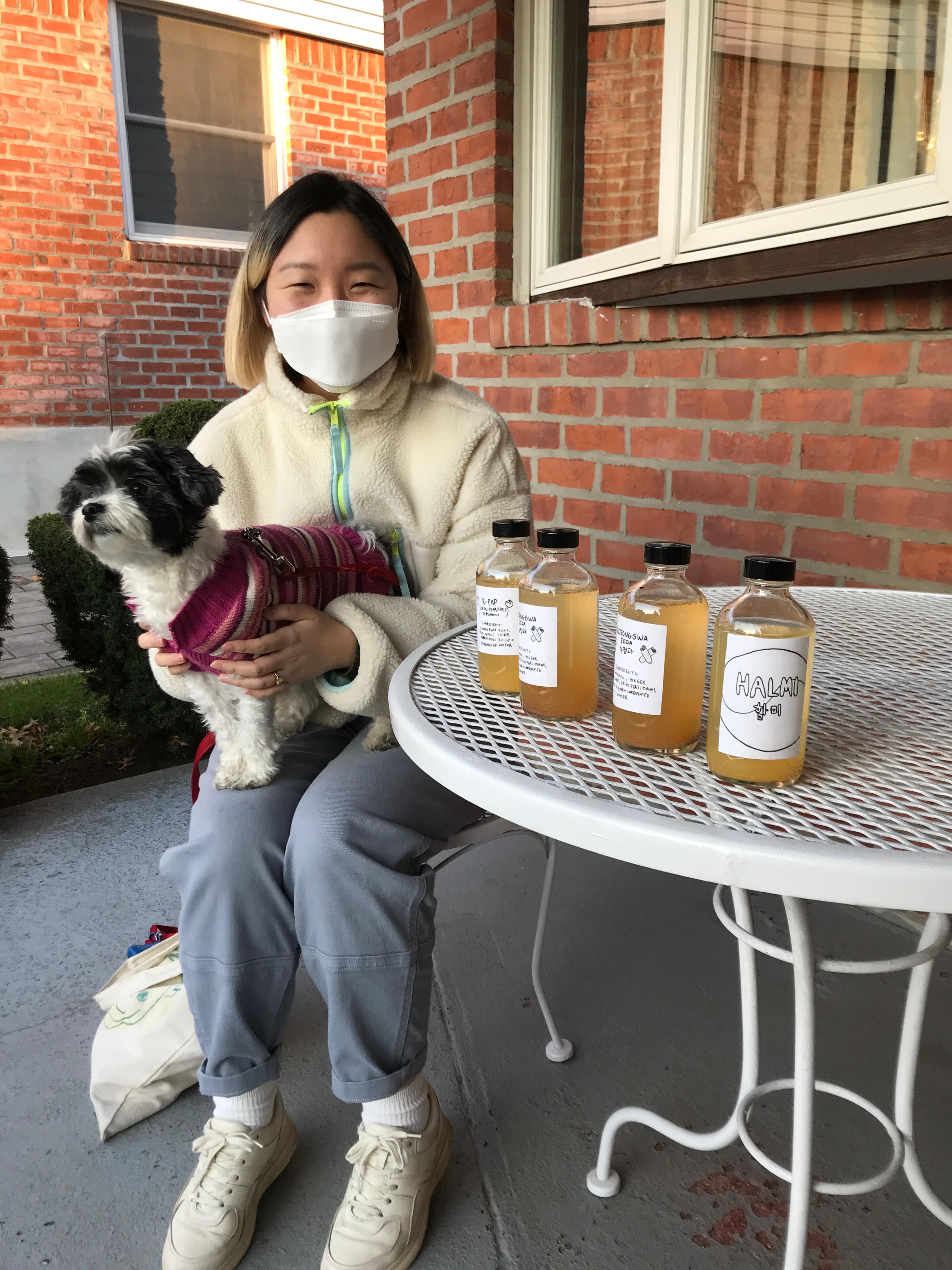 Halmi founder Hannah Bae dropping Halmi bottles at her friends' homes during the pandemic. A dog is on her lap