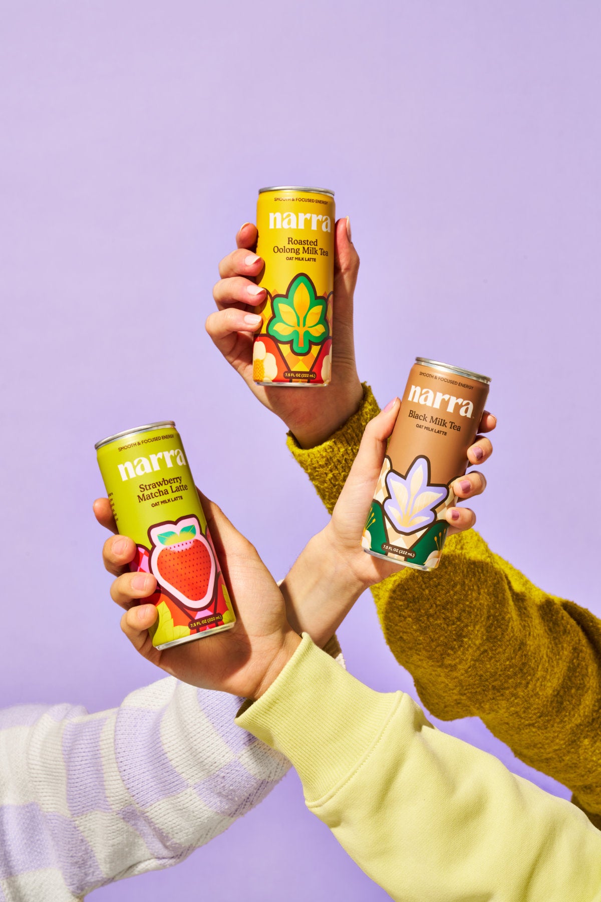 Three hands holding up the three Narra oat milk latte flavors: Strawberry Matcha, Black Milk Tea, and Roasted Oolong Milk Tea.