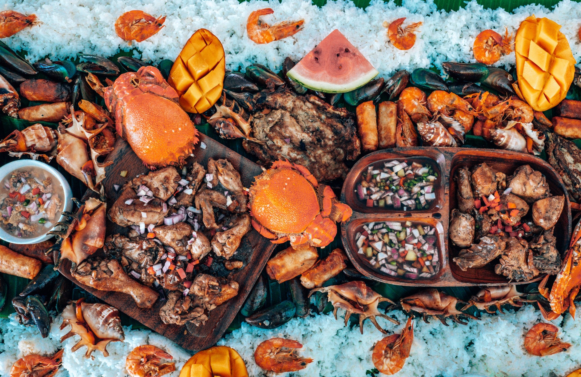 A Filipino Kamayan feast spread out over banana leaves on a table.