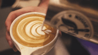Kahve üzerine krema kıvamındaki süt ile latte art yapımı gösterilmektedir.