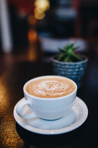 Tezgah üzerinde bol köpüklü bir cappuccino kahve yer almaktadır.