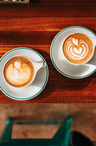 Aynı tezgah üzerinde yan yana yer alan cappuccino ve latte görünmektedir.