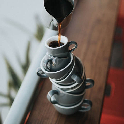 Tezgah üzerinde üst üste yığılı çok sayıda filtre kahve fincanı yer almaktadır. En üstteki fincana kahve doldurulur.