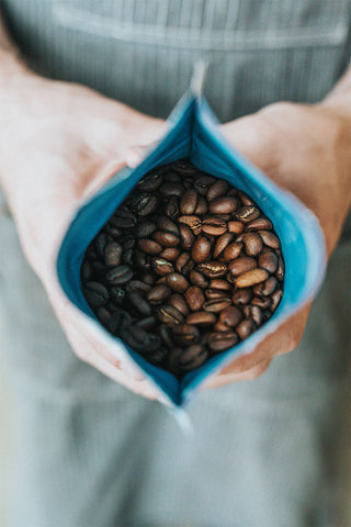 Mavi paket içerisinde yer alan koyu kavrulmuş espresso kahve çekirdekleri.