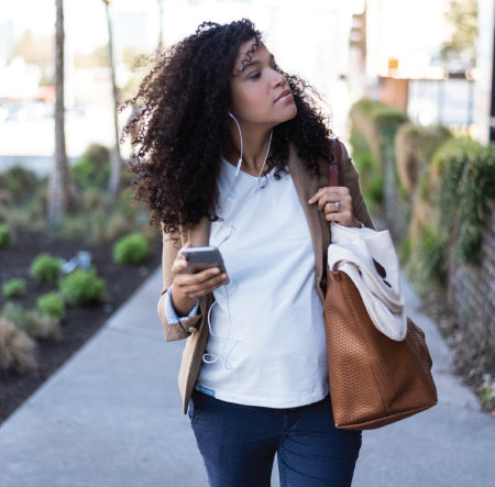 Working, urban mother wearing anti-radiation maternity clothing and cellphone with earbuds