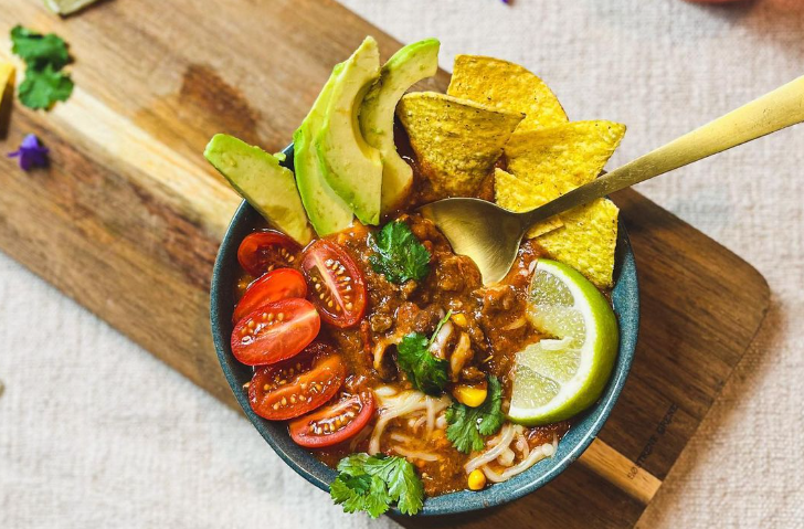 Taco soup with avocado, tomatoes, cilantro and tortilla chips.