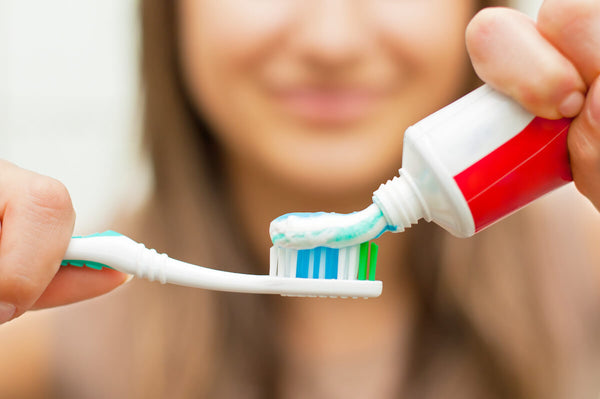 Is xylitol bad for dogs: person putting toothpaste onto a toothbrush