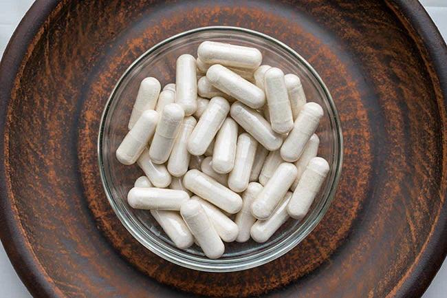 Veg Capsules on round clay brown plate. Herbal Supplements with calming Relaxation, effect, helps support emotional balance. Anti stress herbal pills Dietary Supplement