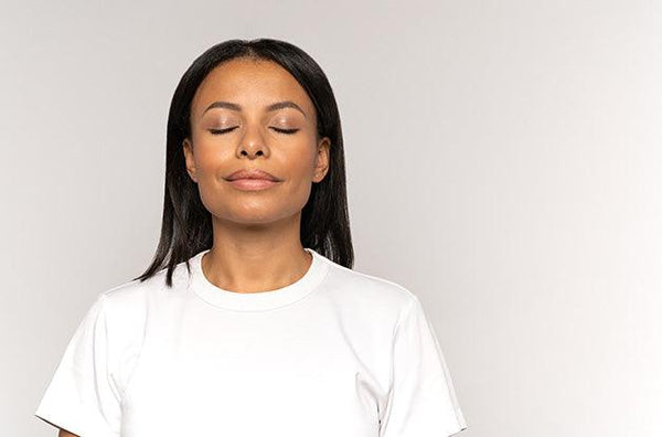 black woman in white tshirt taking deep breaths with a smile