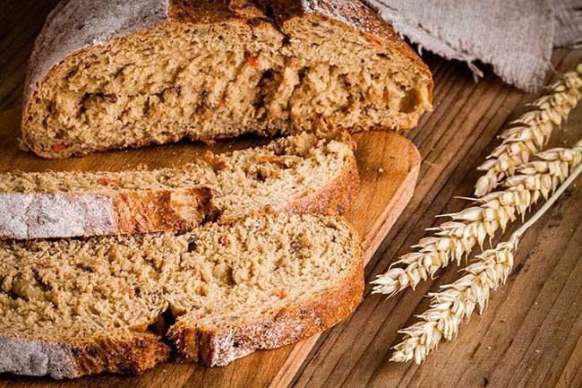 fresh rye bread and grain on a rustic wooden background